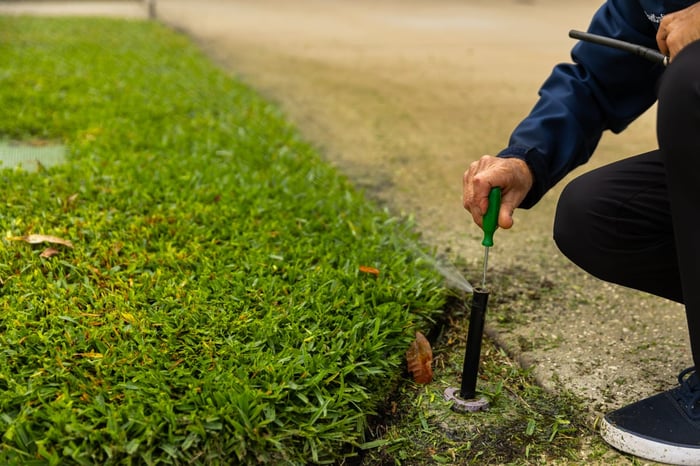 irrigation tech repairing sprinkler head