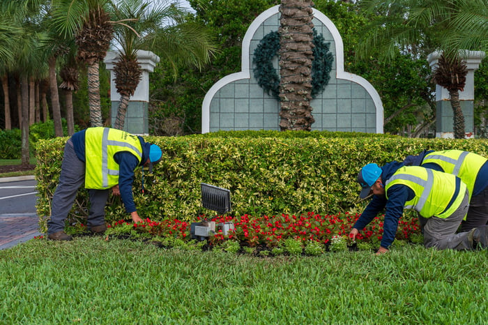 Landscape crew removing weeds from front entrance flower beds