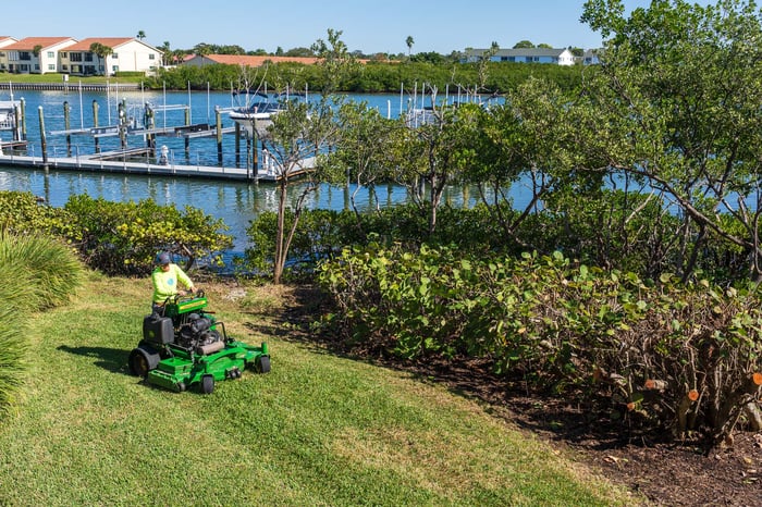 Landscape maintenance crew mowing along water 4