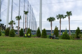 landscaping crew along top golf net enclosure 
